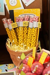 A basket full of candy pencils with a basket of candy apples in the foreground