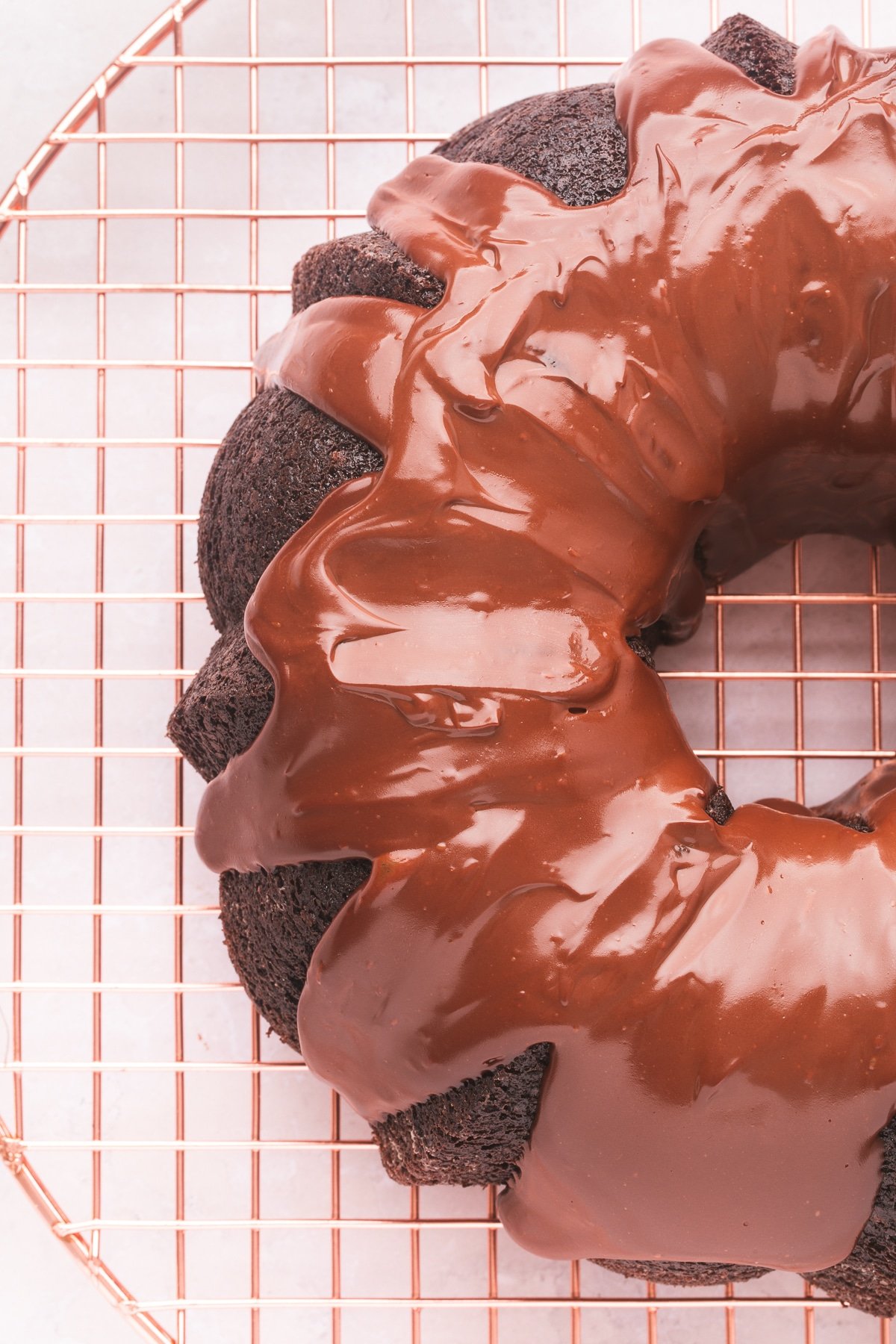 Overhead view of a chocolate bundt cake with ganache on a cooling rack