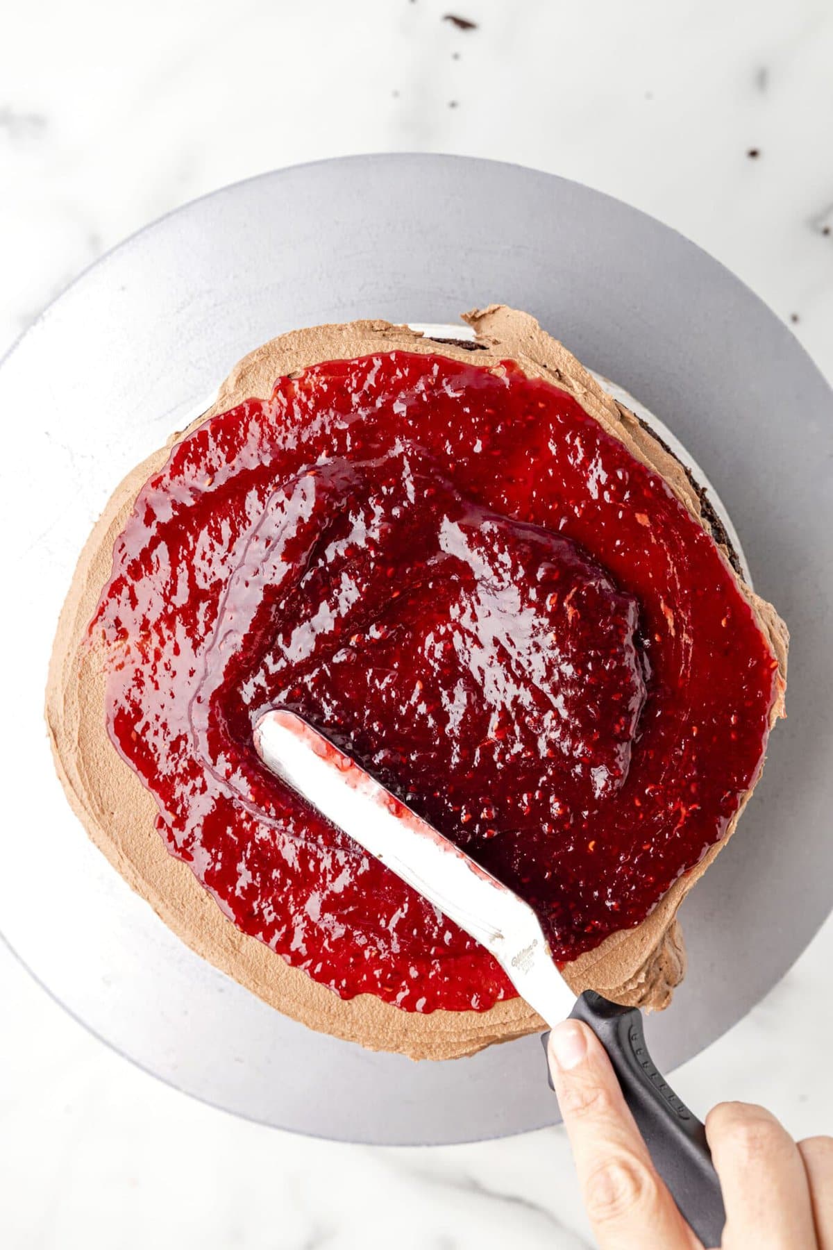 Adding a layer of the raspberry preserves over chocolate cake.