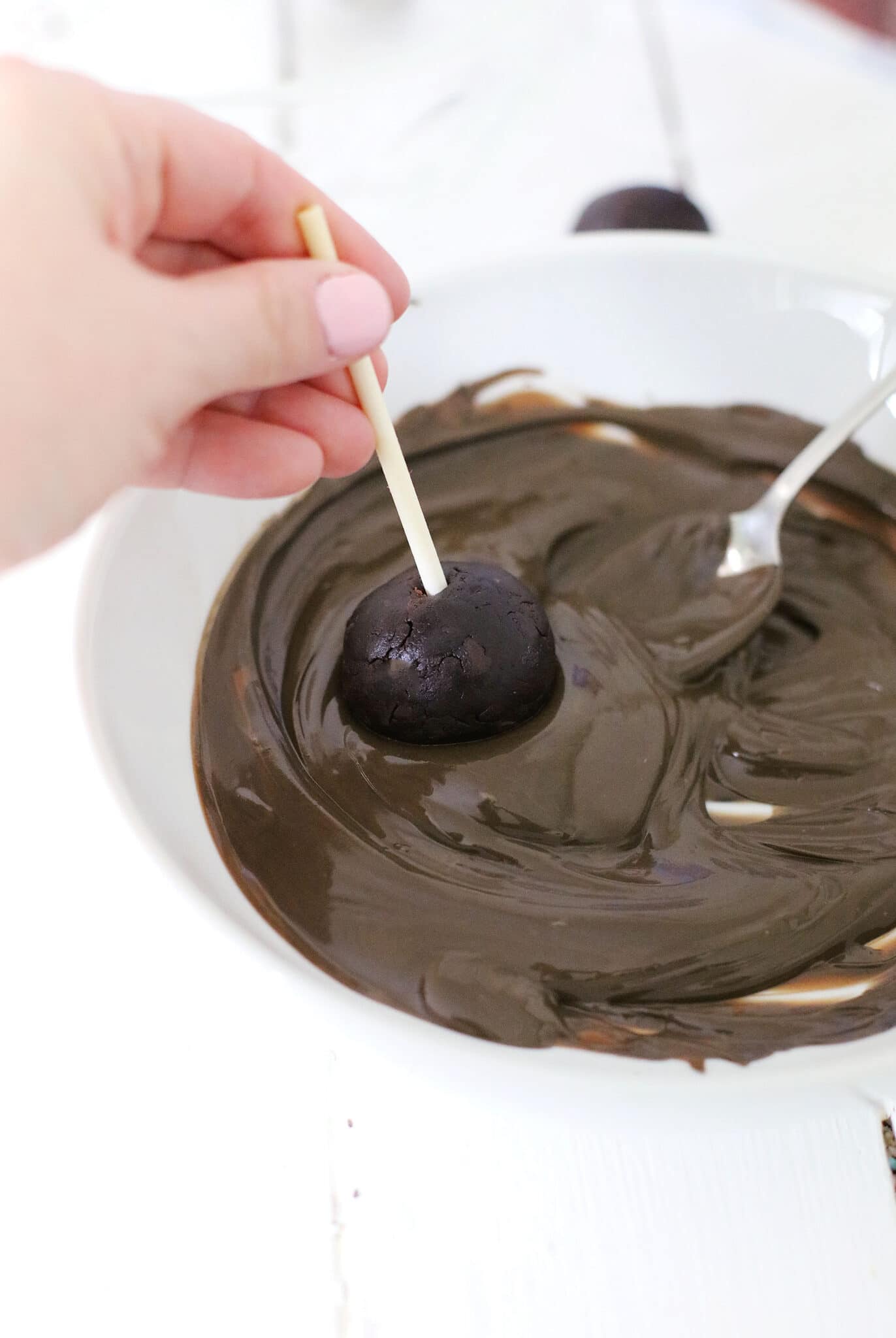 Dipping the cake into the chocolate.