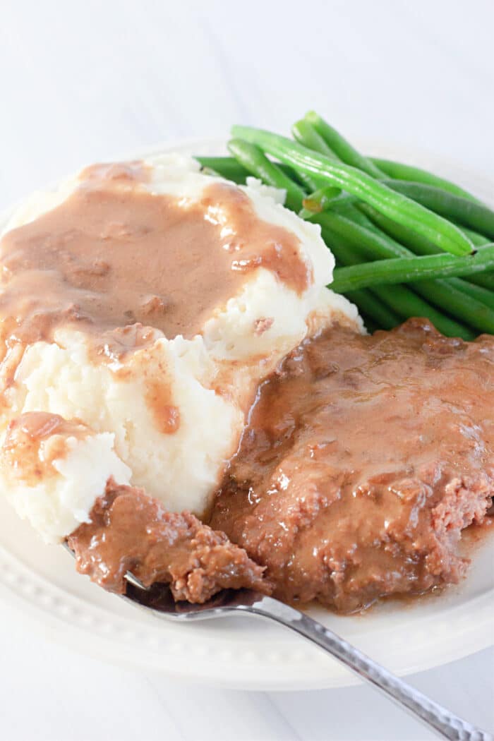 a plate of mashed potatoes, green beans, and cube steak with gravy.