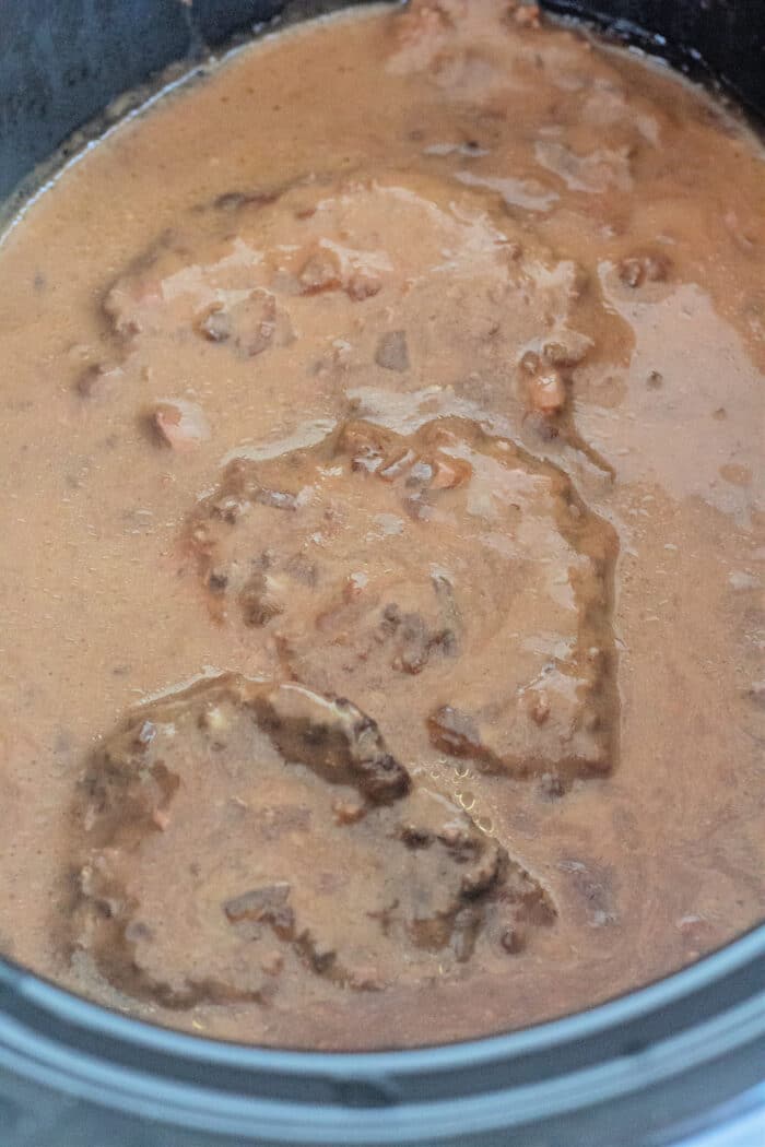 freshly made Crock Pot Cube Steak with Gravy in a black slow cooker.