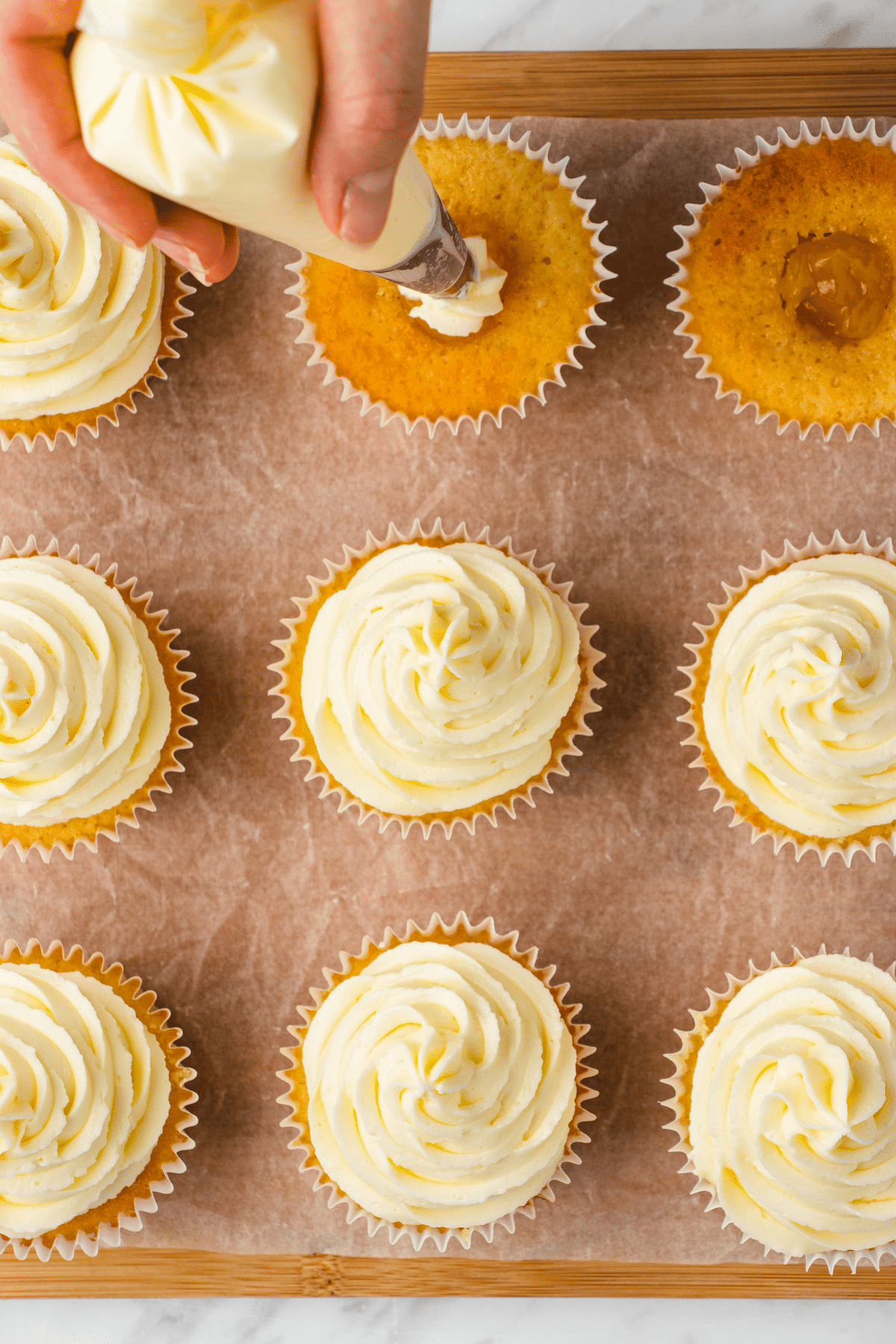 Cupcakes being topped with lemon buttercream filling