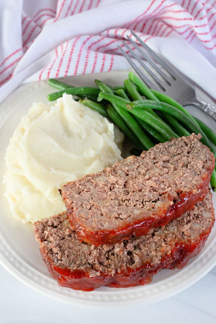 Slices of Stove Top Stuffing Meatloaf with mashed potatoes and green beans.