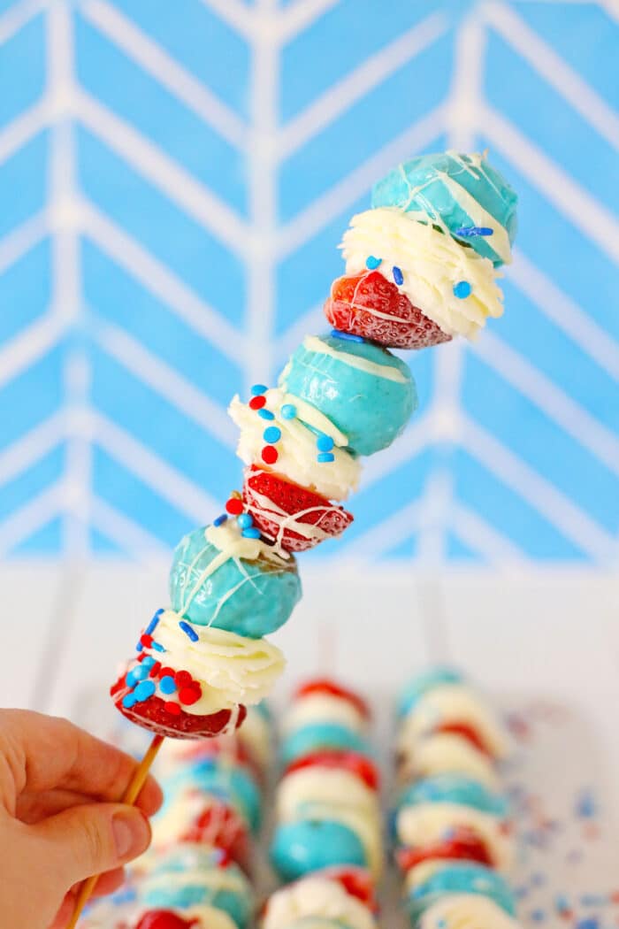A hand lifting up one of the Patriotic Donut Kabobs.