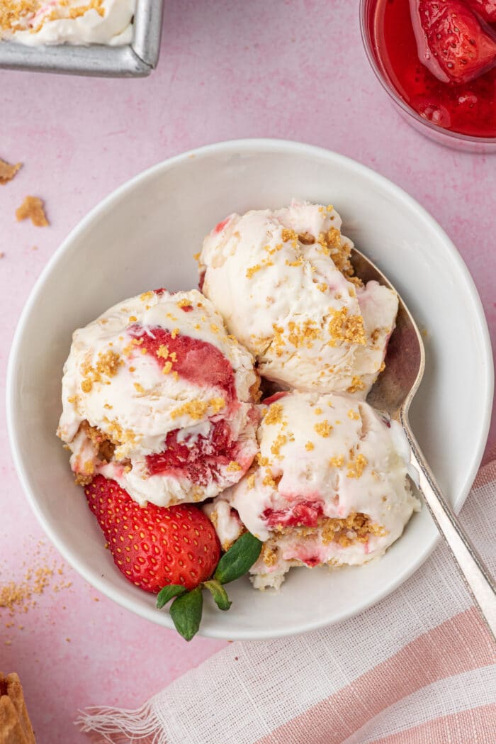 A spoon in the bowl of Strawberry Cheesecake Ice Cream.