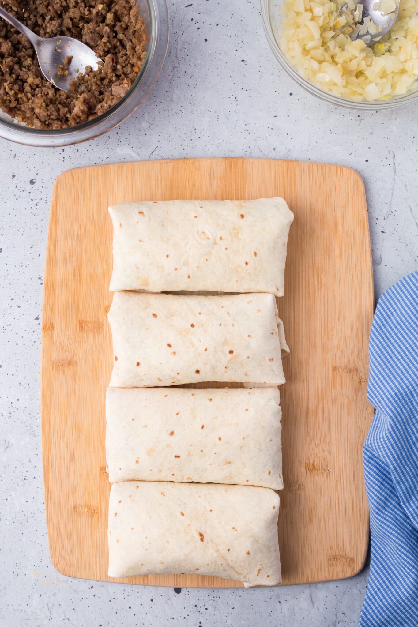 The folded burritos on the cutting board.