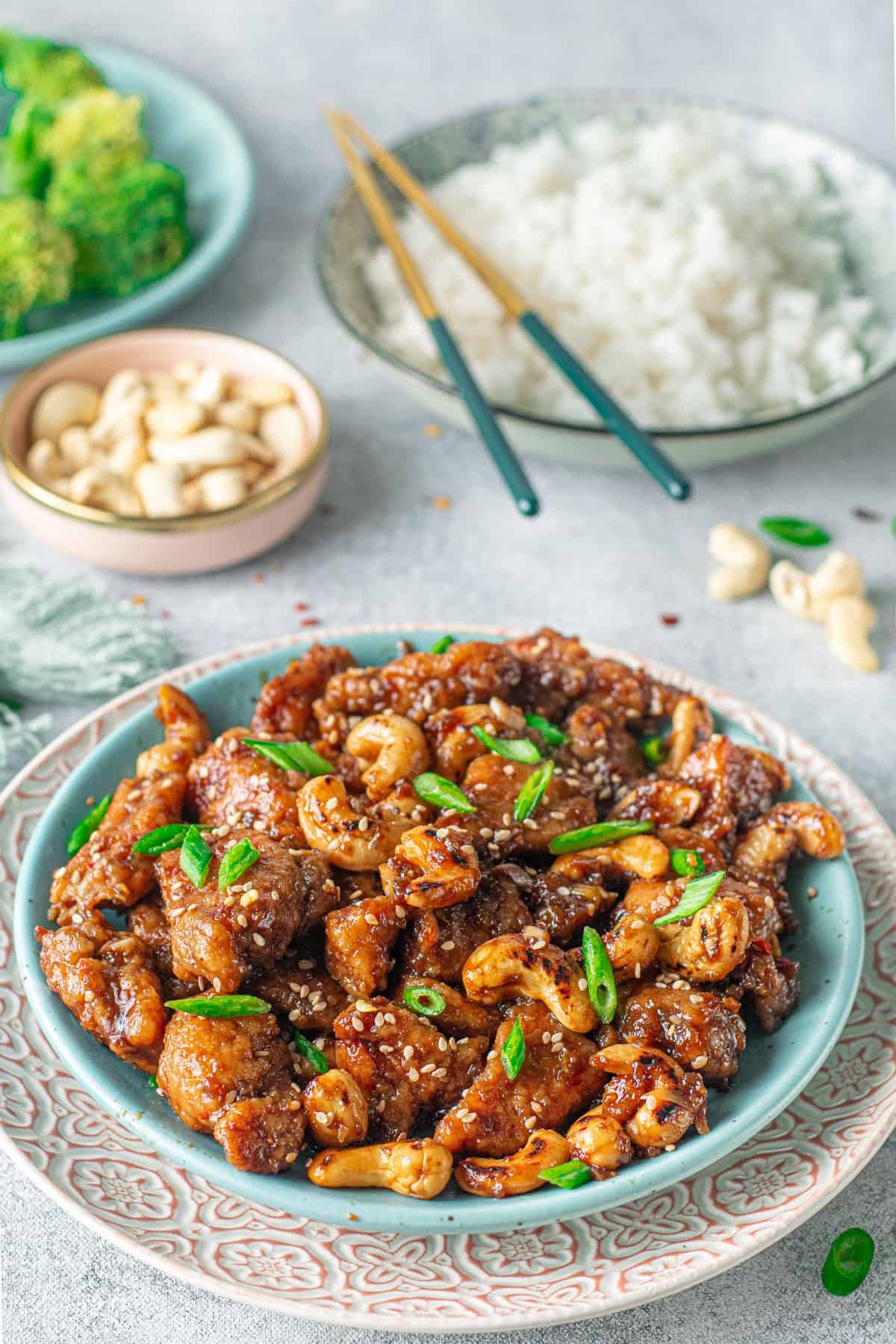 Tender, juicy pieces of chicken and toasted cashews are tossed in a sticky sweet-but-savory garlic sauce in this Cashew Chicken recipe. A blue plate of cashew chicken