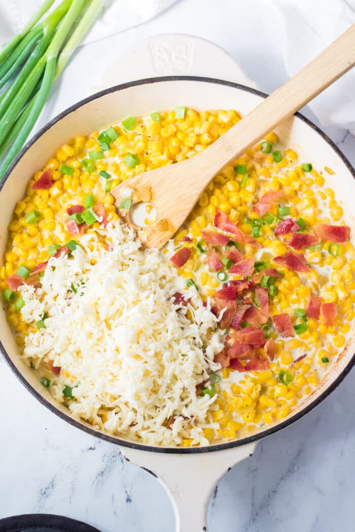 Adding in the cheese to the corn in a skillet