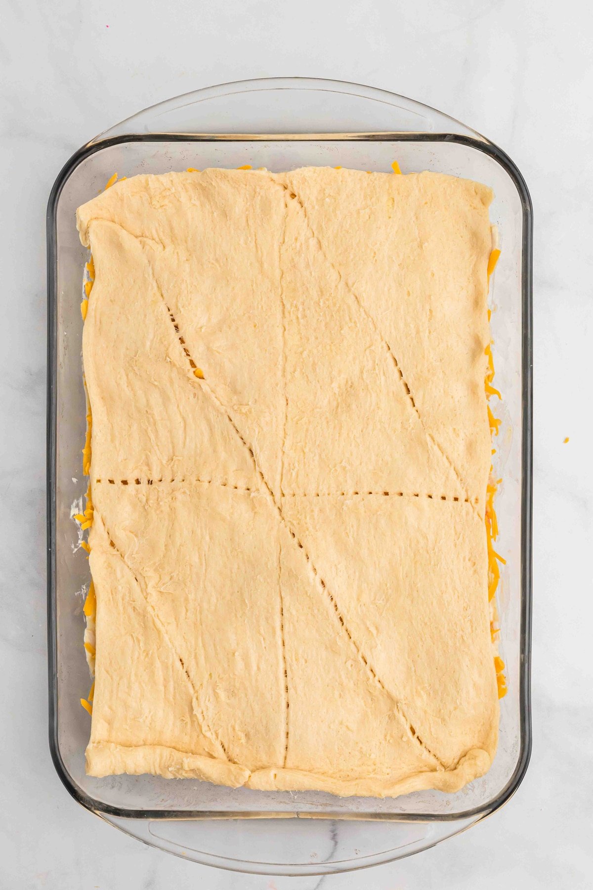 Crescent roll dough spread over chicken pot pie filling in a casserole dish