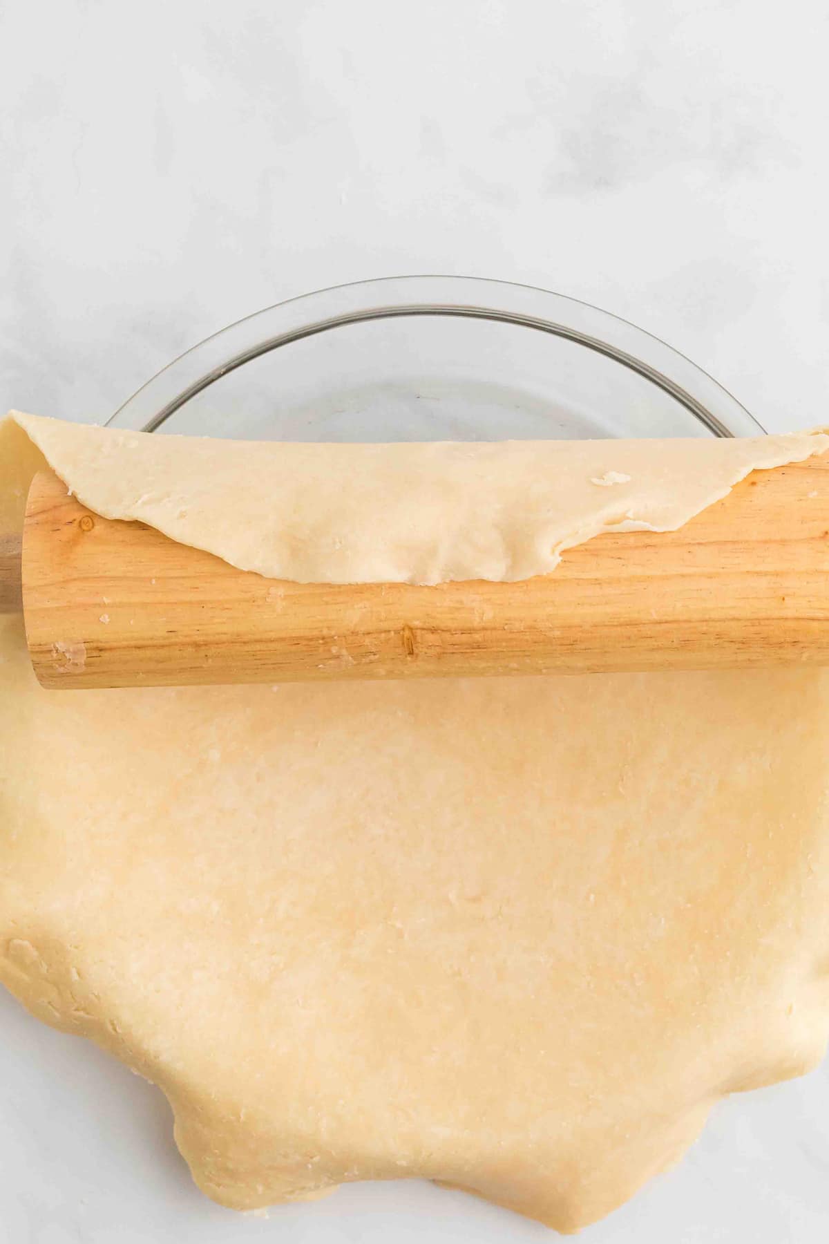 The rolled out pie crust being spread in the pie pan
