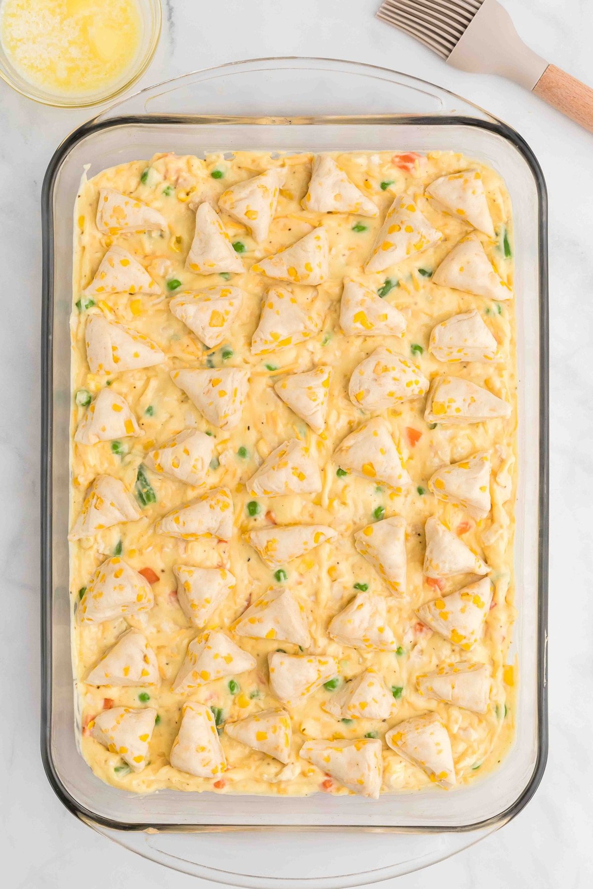 Chicken pot pie filling topped with biscuits in a casserole dish
