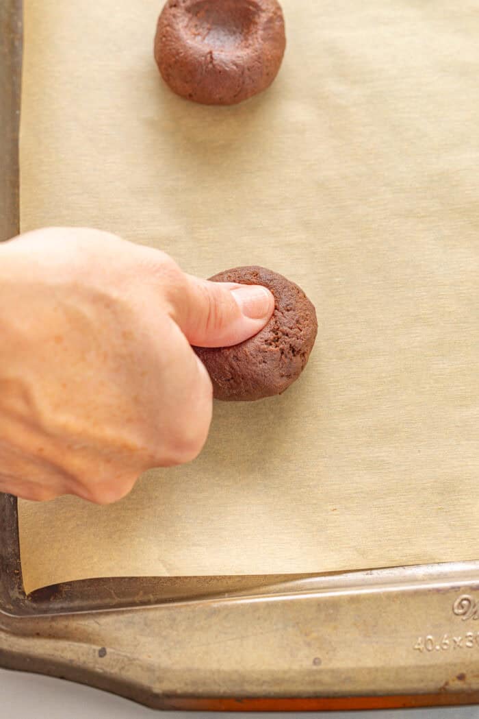 Pressing a thumb into a ball of cookie dough