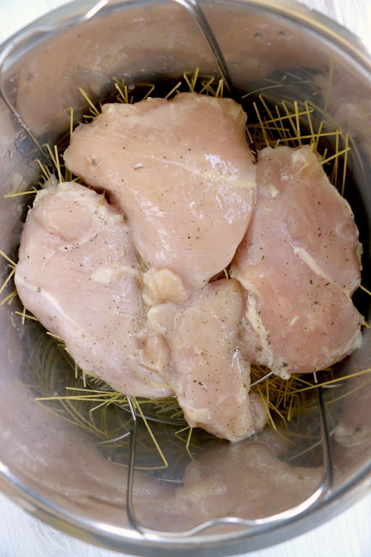 Adding the raw chicken to the instant pot.