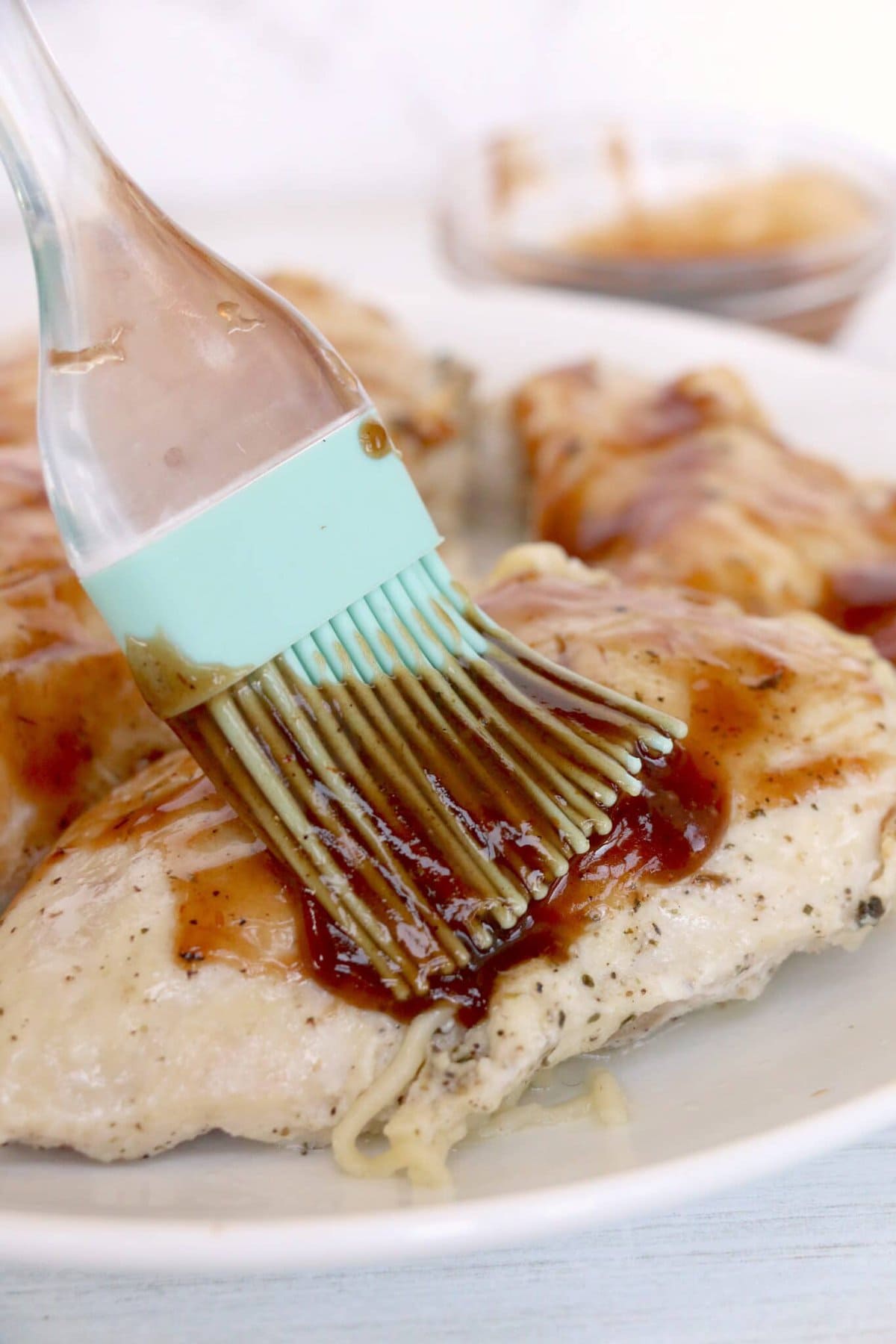 Brushing the chicken with BBQ sauce.