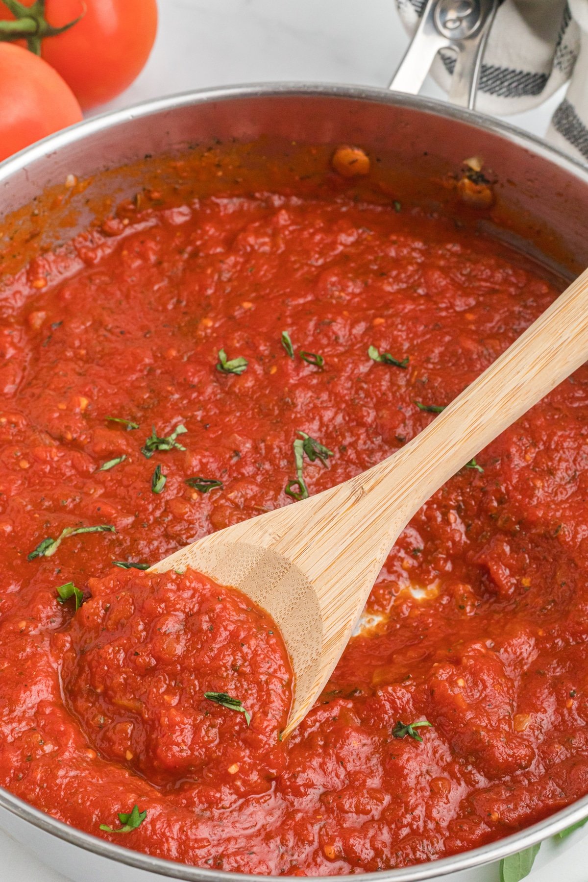 A wooden spoon stirring marinara sauce