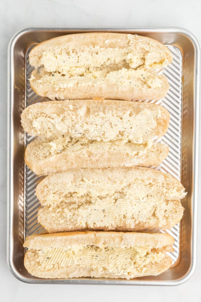 Hoagie rolls with garlic butter on a baking sheet