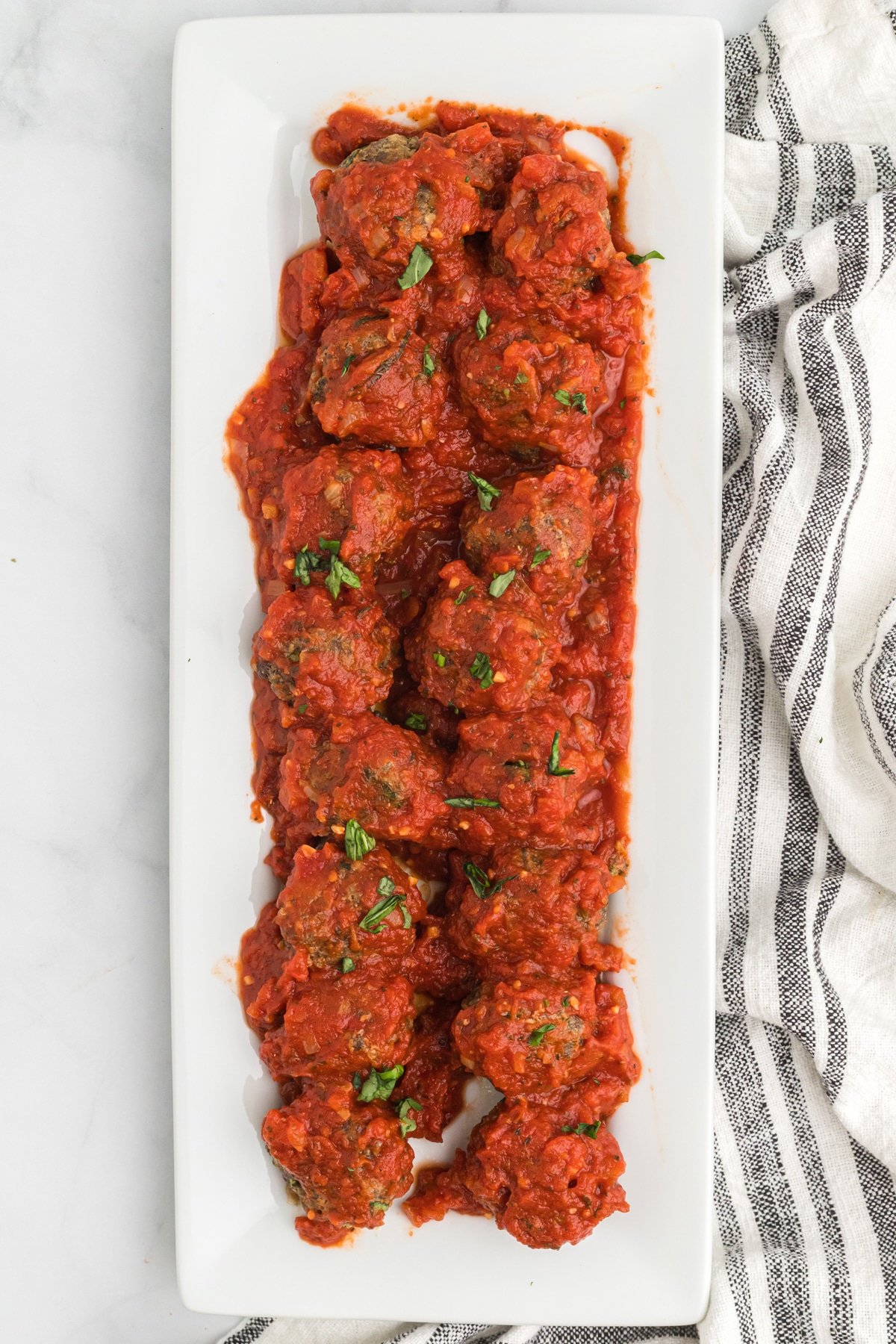 Meatballs covered in marinara sauce on a serving platter