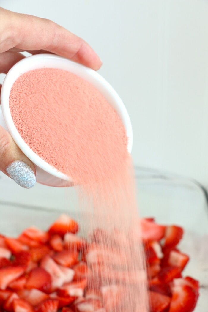 pouring jello mix over strawberries