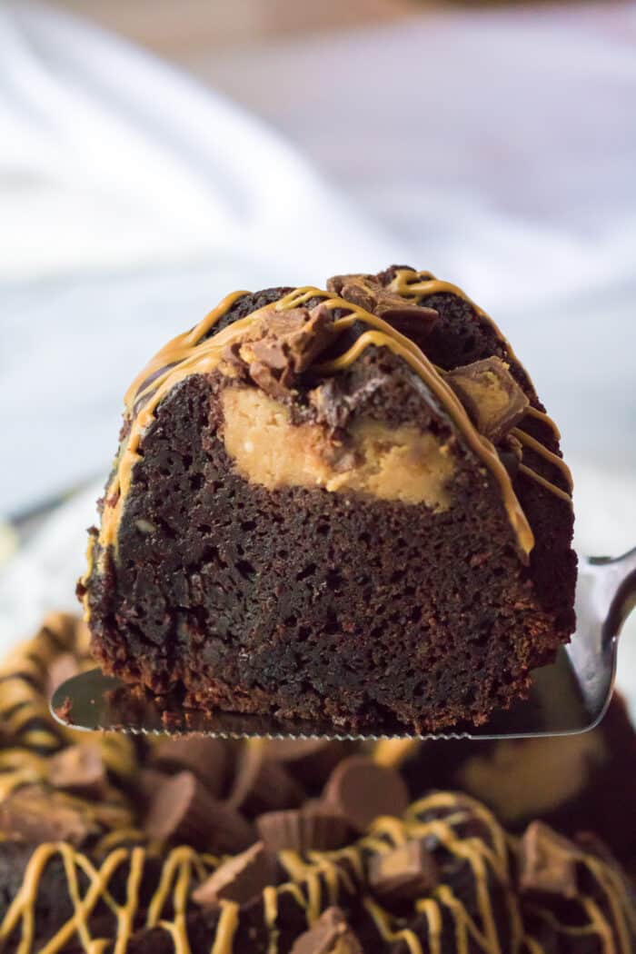 A spatula lifting up a piece of the Chocolate Peanut Butter Bundt Cake.