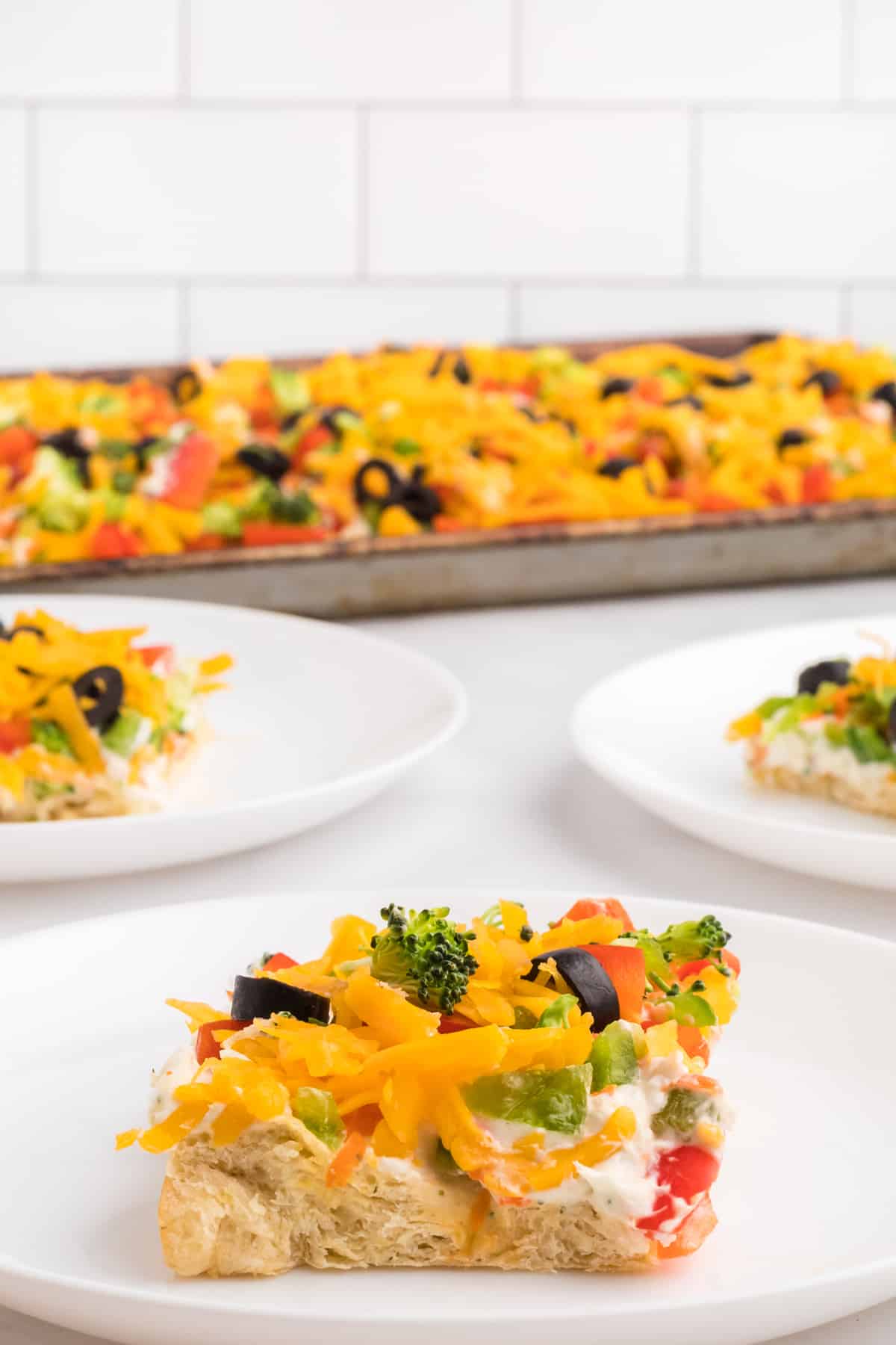 A square of cold veggie pizza on a white plate