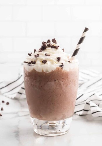 A frozen hot chocolate in a glass topped with whipped cream and chocolate chips
