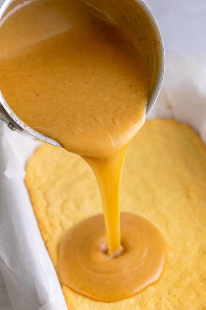Pouring caramel over shortbread in a baking dish