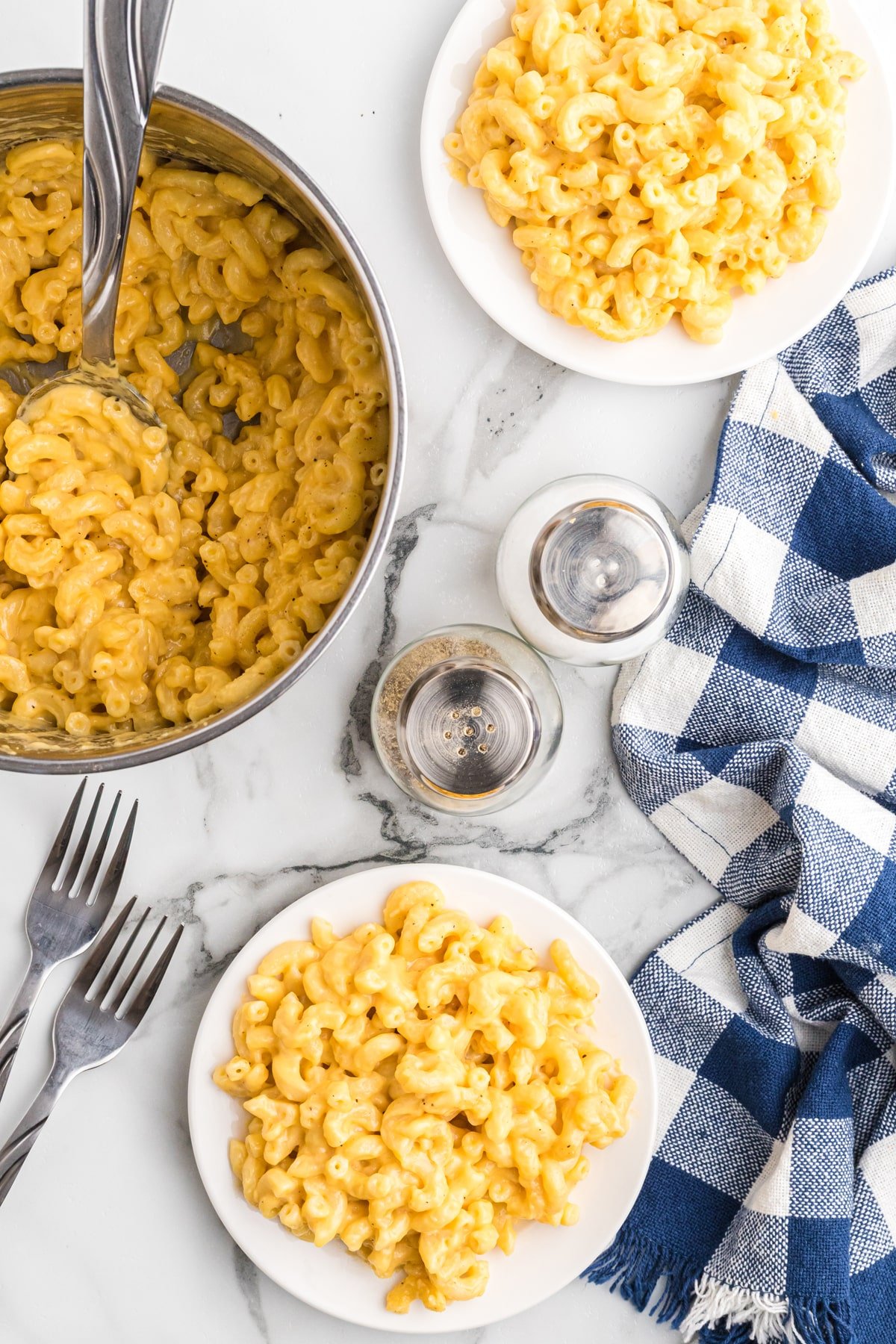 Overhead view of a pan of mac and cheese and two plates of mac and cheese