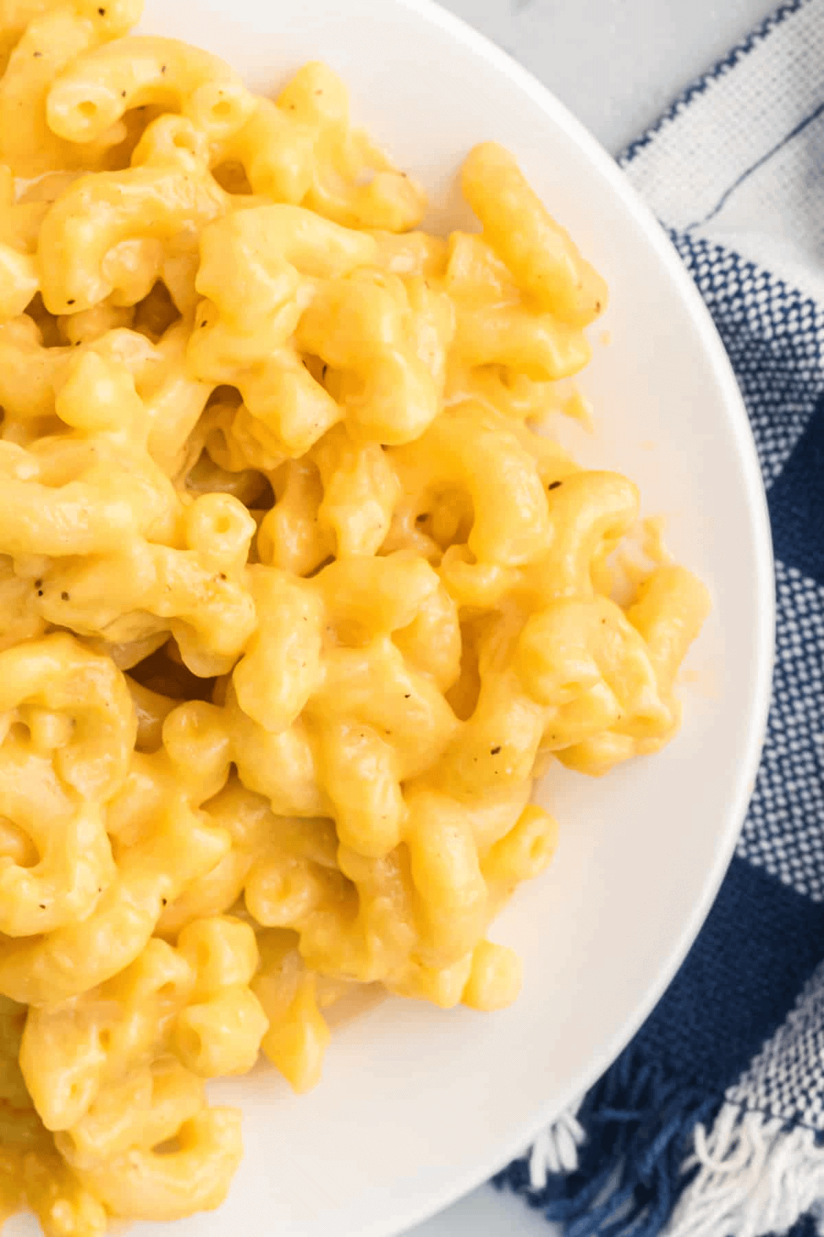 This stovetop mac and cheese is made with sour cream and whole milk for extra creaminess, and it comes together in under 30 minutes! Creamy mac and cheese on a white plate.