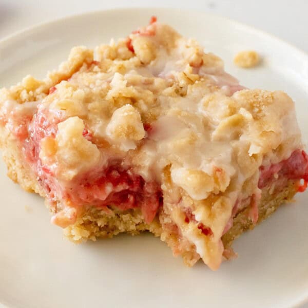A strawberry bar with a bite missing on a plate.