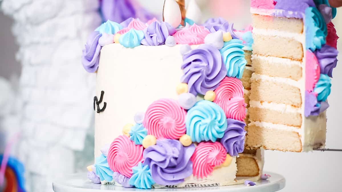 The back of a unicorn cake with a piece being sliced