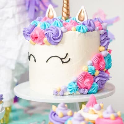 Side view of a unicorn layer cake on a cake stand