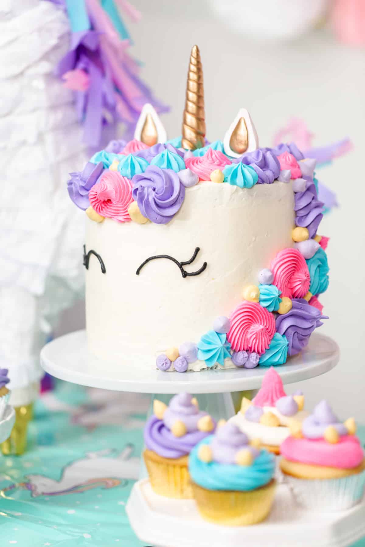 Side view of a unicorn layer cake on a cake stand