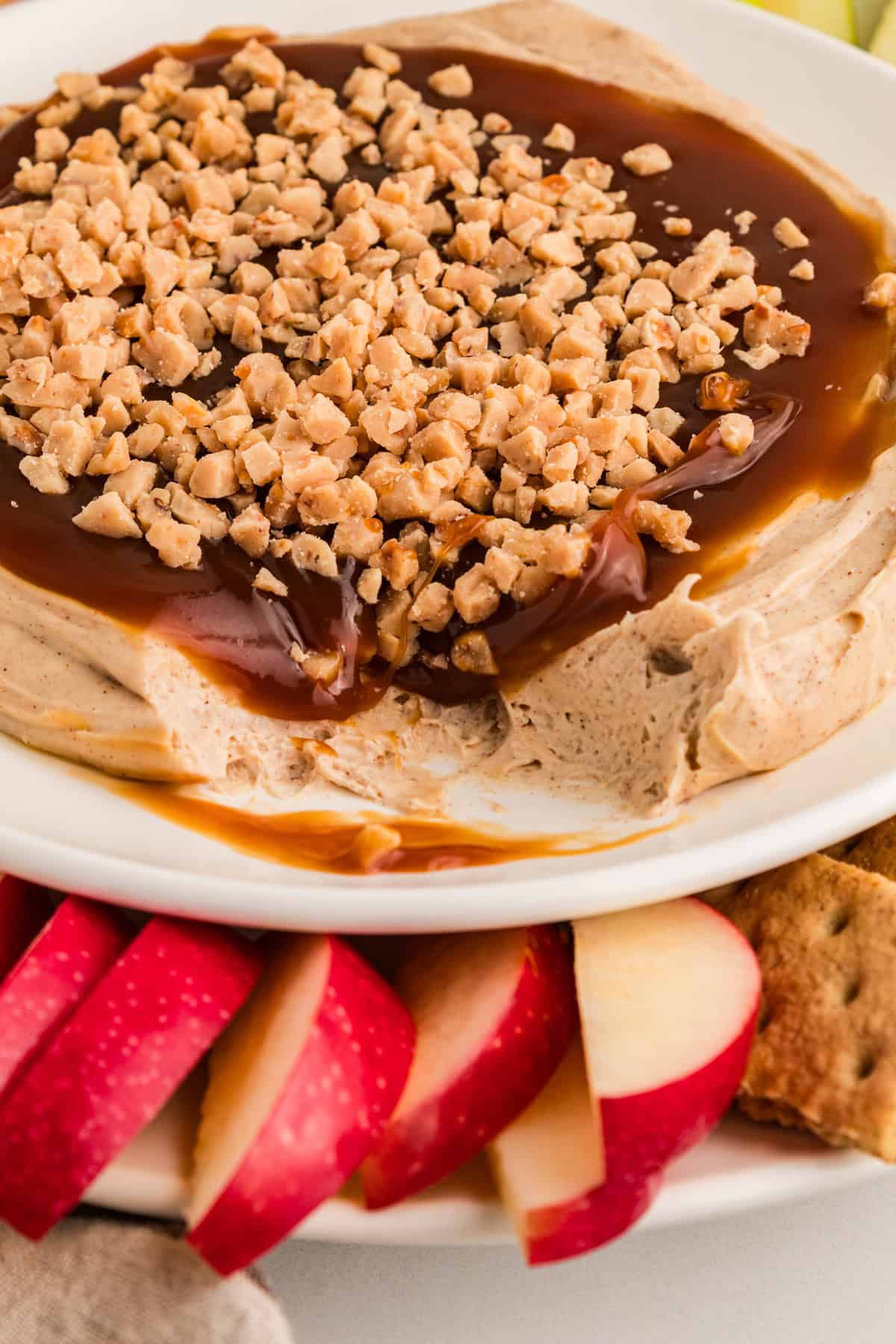 Ready in 5 minutes, this Caramel Apple Dip is made with cream cheese, brown sugar, and caramel sauce for an easy fall treat. Caramel apple dip on a plate with apple slices in front