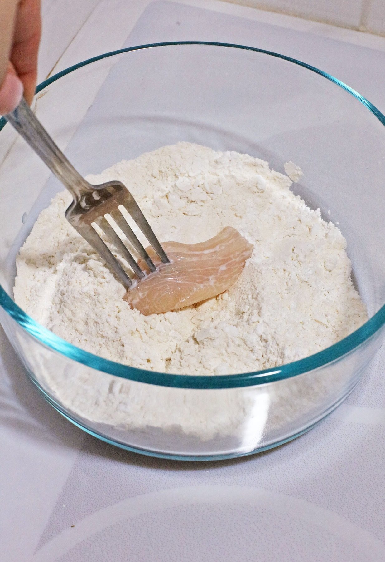 Dipping the chicken in flour.