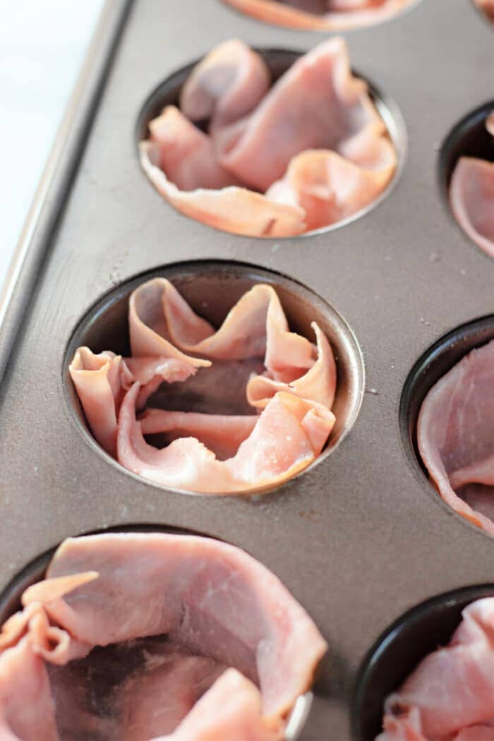 placing the ham into muffin tin wells.