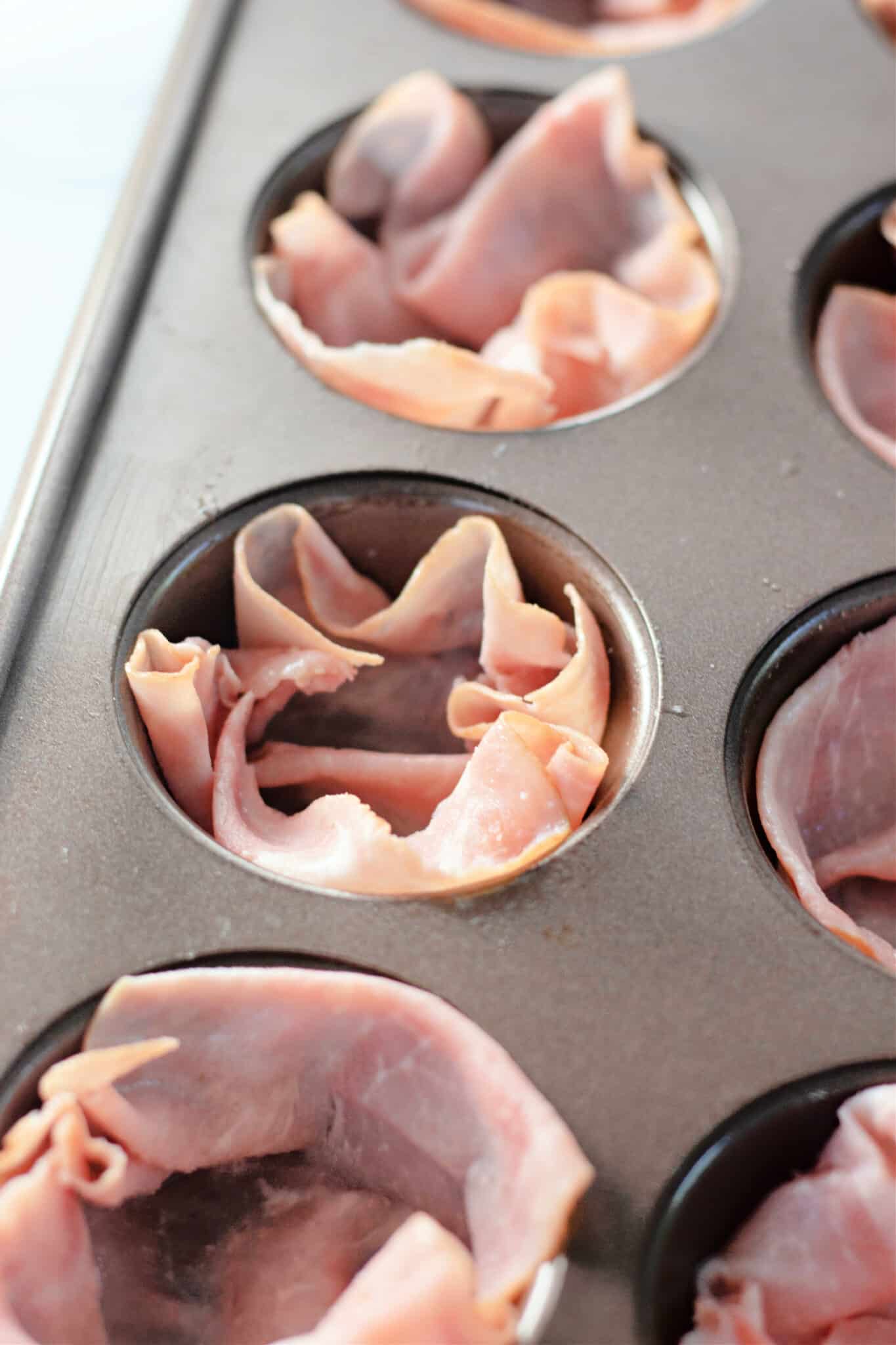 placing the ham into muffin tin wells.