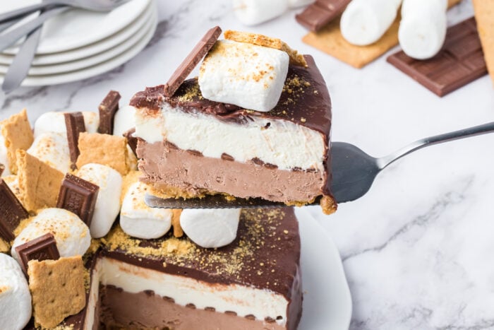 A spatula lifting up a slice of S'mores Cheesecake Recipe.