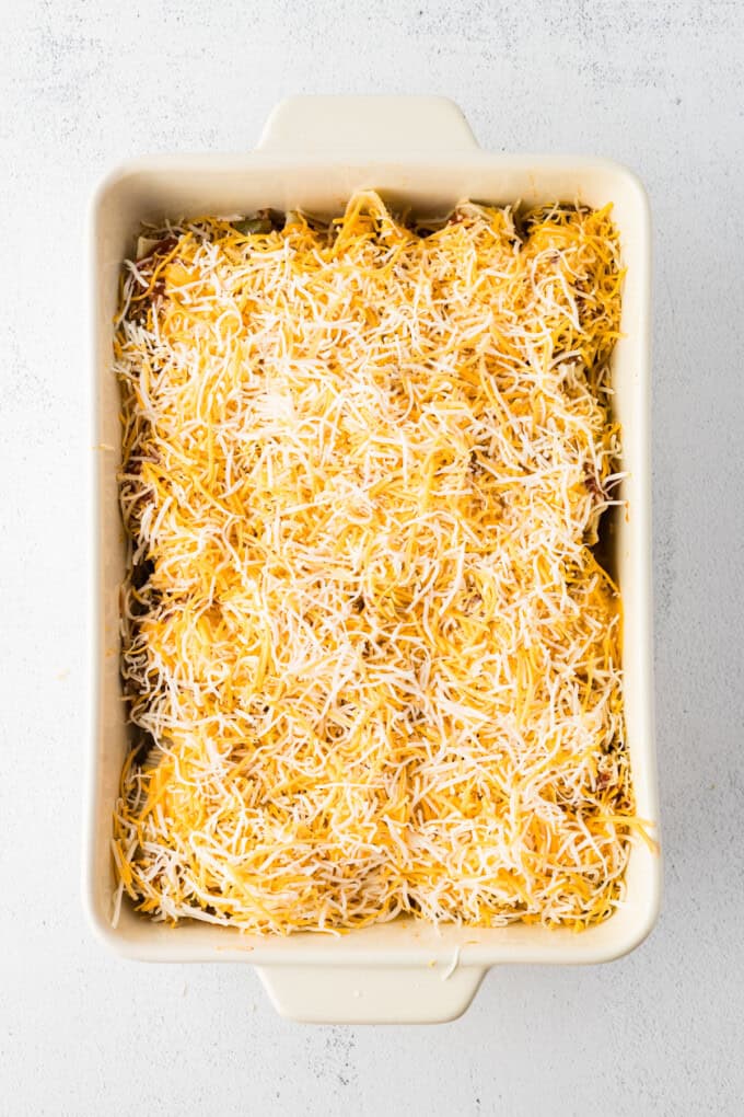 Jumbo shells are stuffed with seasoned ground beef and topped with queso, taco sauce, and shredded cheese to make these Taco Stuffed Shells. Shredded cheese sprinkled over the stuffed shells