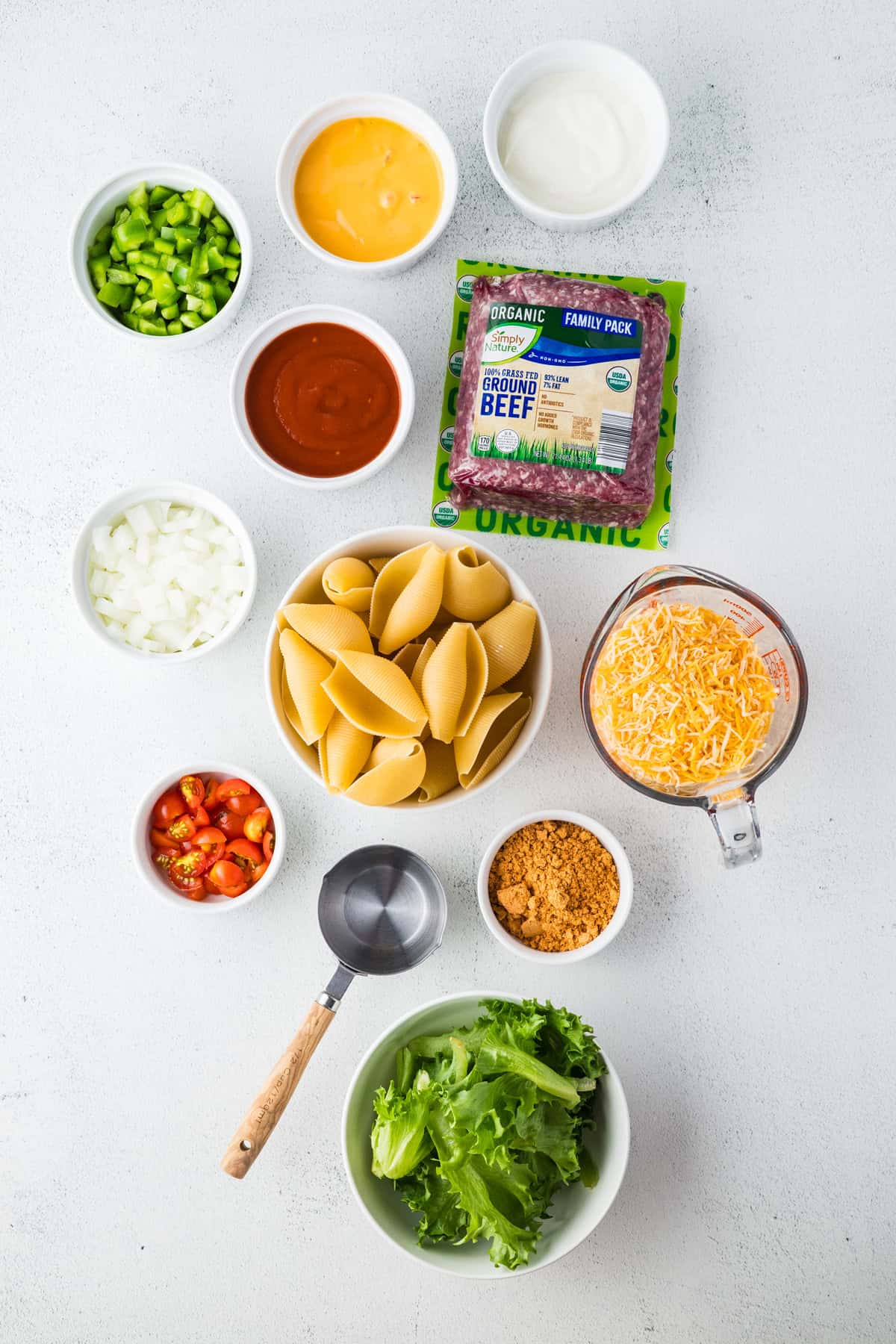 Jumbo shells are stuffed with seasoned ground beef and topped with queso, taco sauce, and shredded cheese to make these Taco Stuffed Shells. Overhead view of ingredients needed to make taco stuffed shells