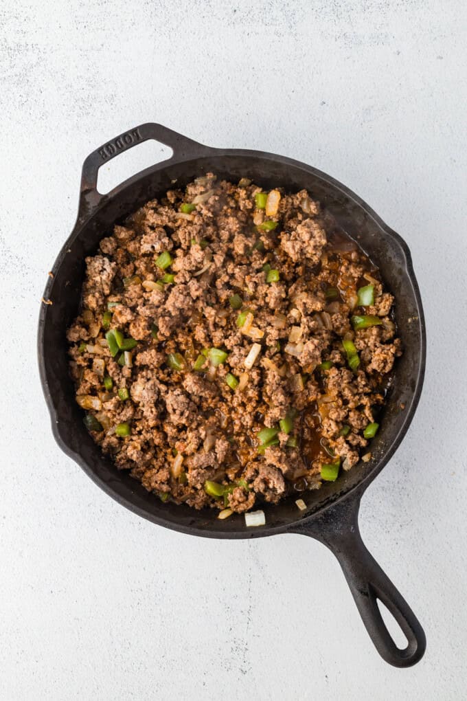 Jumbo shells are stuffed with seasoned ground beef and topped with queso, taco sauce, and shredded cheese to make these Taco Stuffed Shells. Cooked ground beef, onions, and peppers in a pan