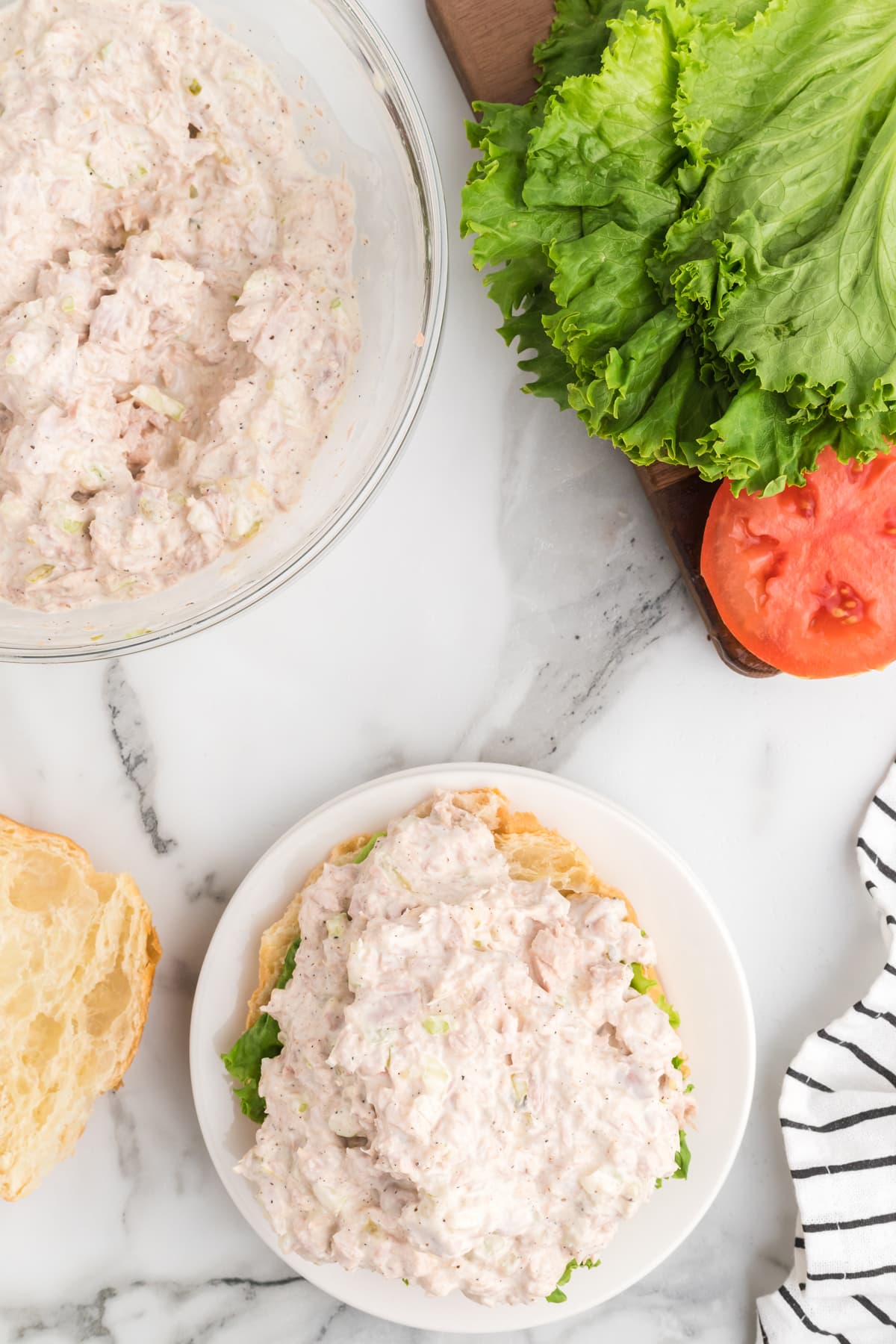 Overhead view of tuna salad on a croissant with a bowl in the background