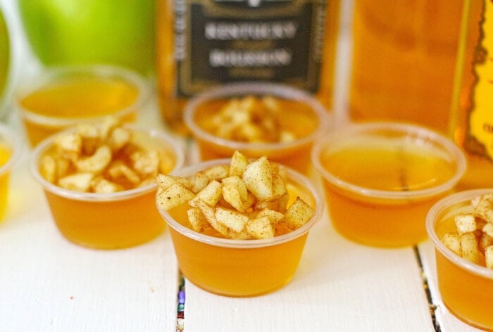 Apple Cider Bourbon Shots with the bourbon bottle in the background.