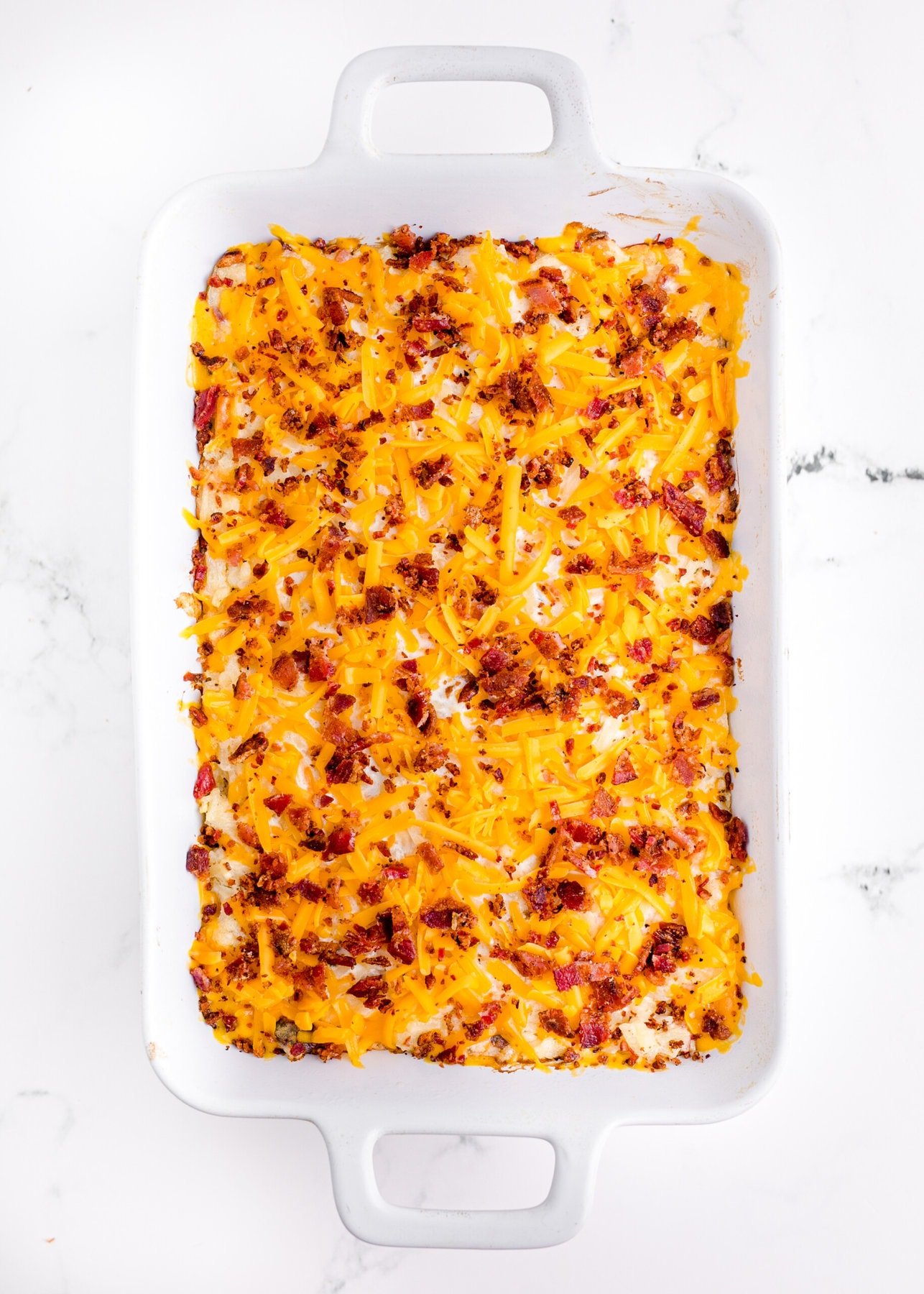 Putting the bacon and cheese on the Loaded Potato Casserole.