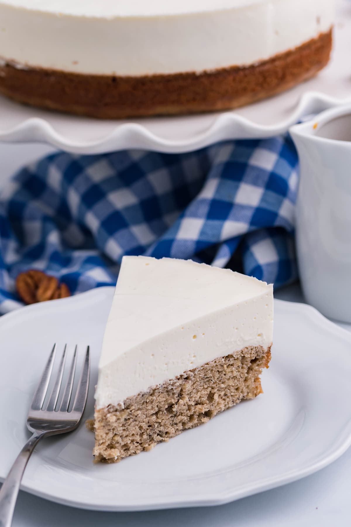 Angled view of a slice of banana bread cheesecake on a white plate