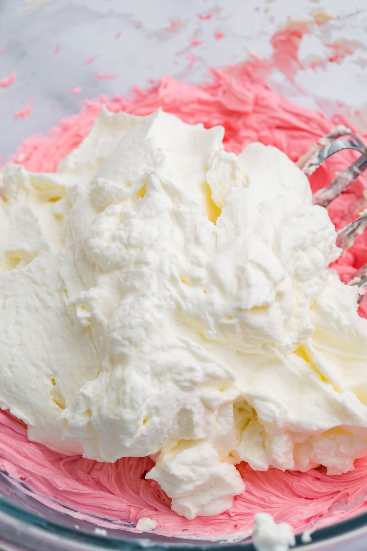 Red cream cheese and whipped cream in a mixing bowl