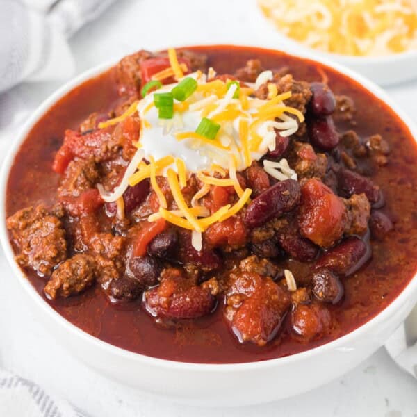A bowl of chili with cheese and green onions for garnish.