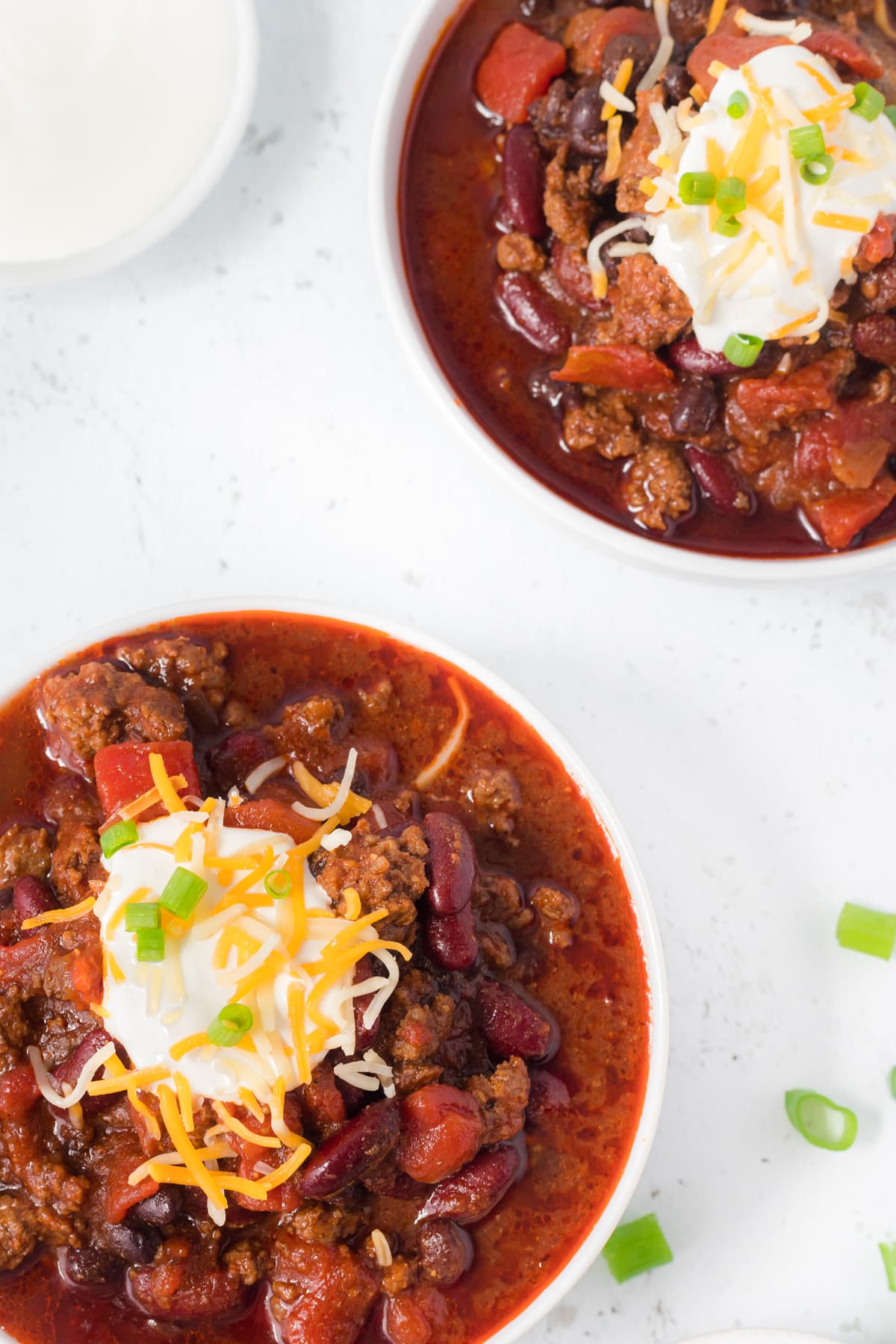 Two bowls of chili with garnish.