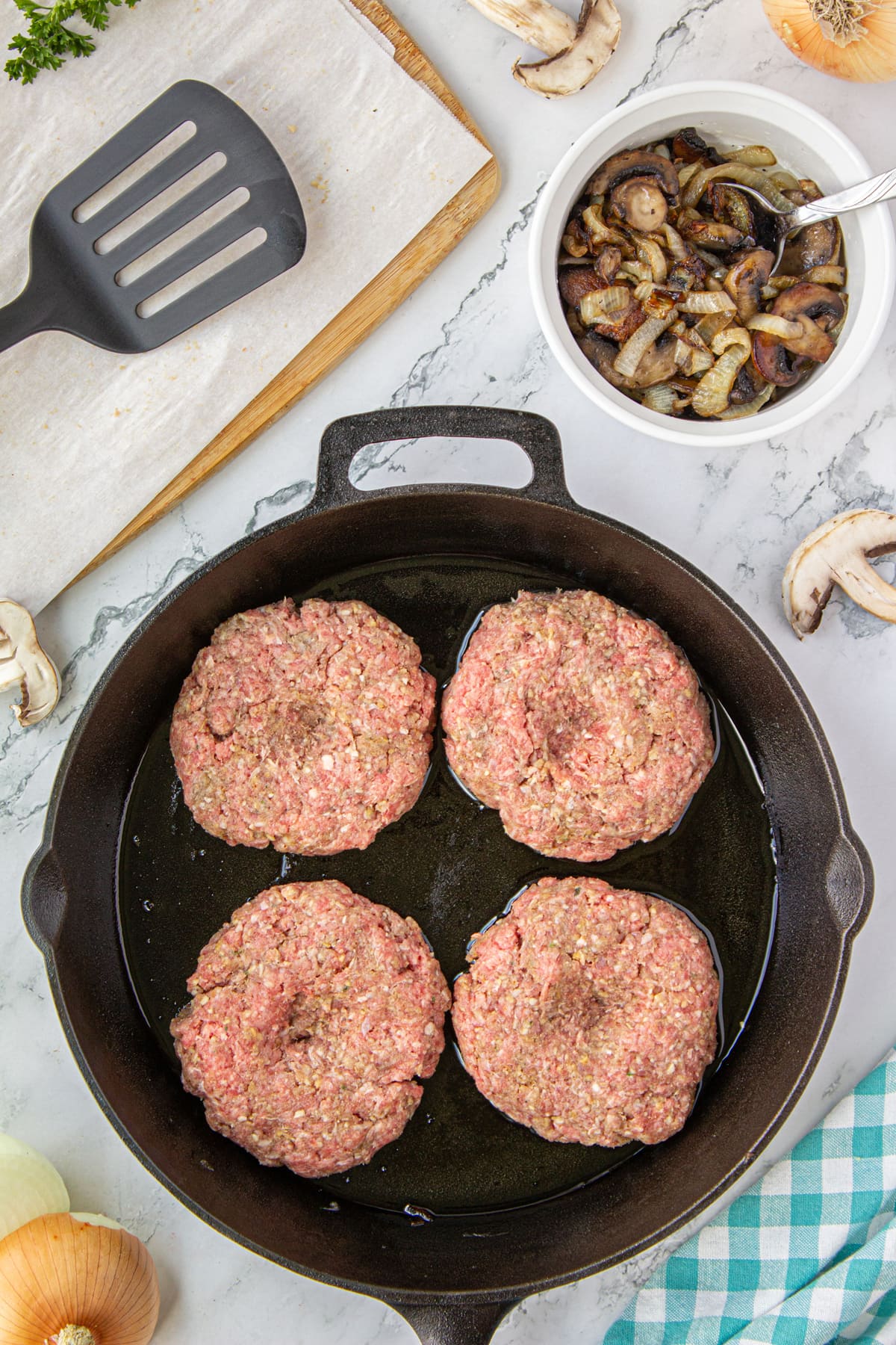A pan with four hamburger steak patties sitting in oil at the bottom.
