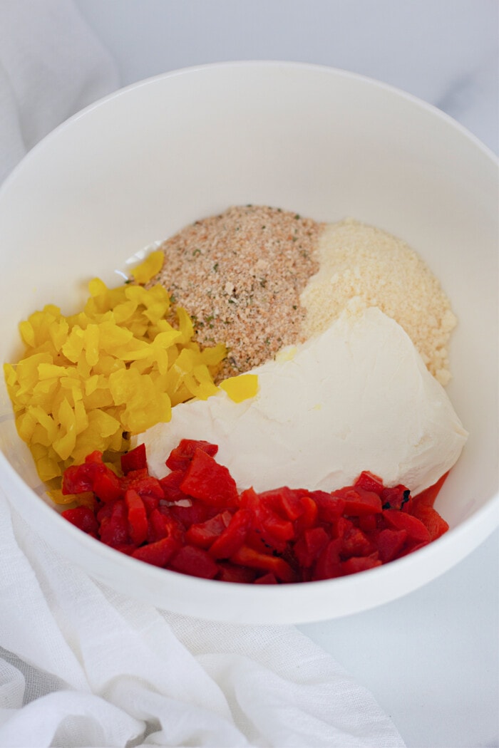 cream cheese, parmesan cheese, Italian breadcrumbs, and chopped peppers in a white bowl.